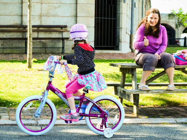 Woman giving thumbs up to girl on a bike