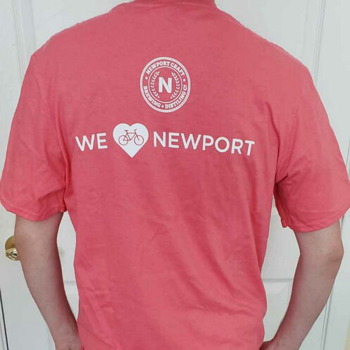 Bike Newport Summer '22 shirt back. Pink shirt with text "We (bike)heart Newport"