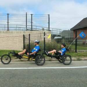 two riders in blue on recumbant adaptive bikes