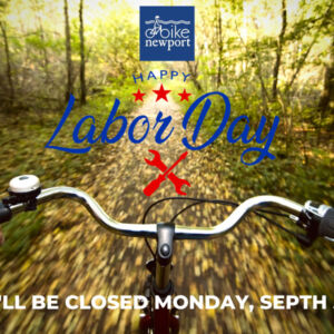 Point of view riding a bike on a leafy road with "closed Labor Day" text