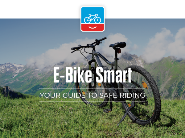 E-Mountain bike parked in the grass by a mountain with the text "E-Bike Smart, your guide to safe riding"