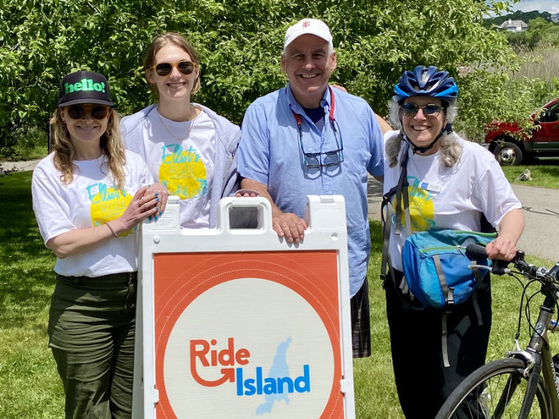 Four team leaders with the Ride Island logo sandwich board