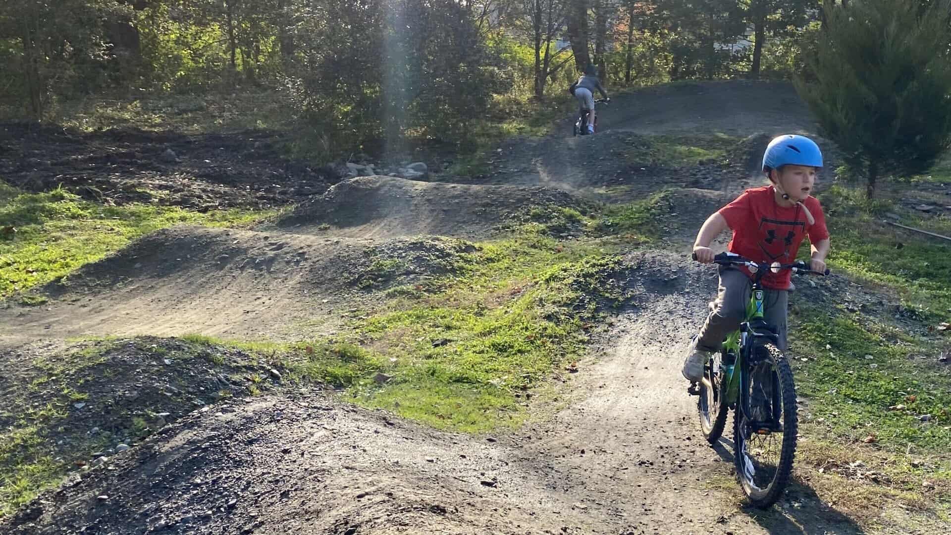 Child in a red shirt on a bike at the Newport Pump Track