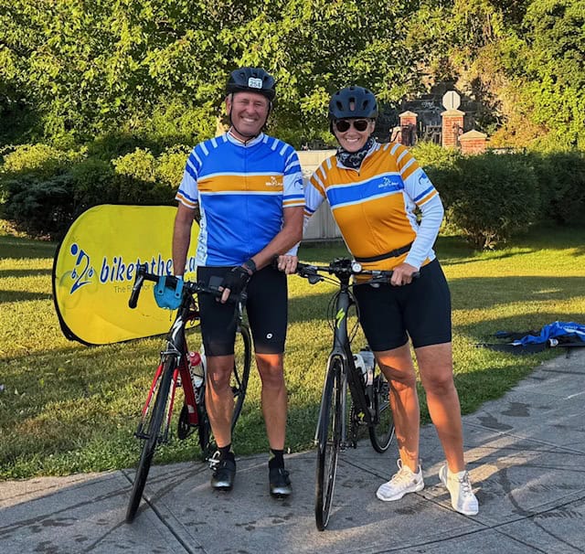 Bike Newport cycling event with smiling cyclists in front of a branded banner.