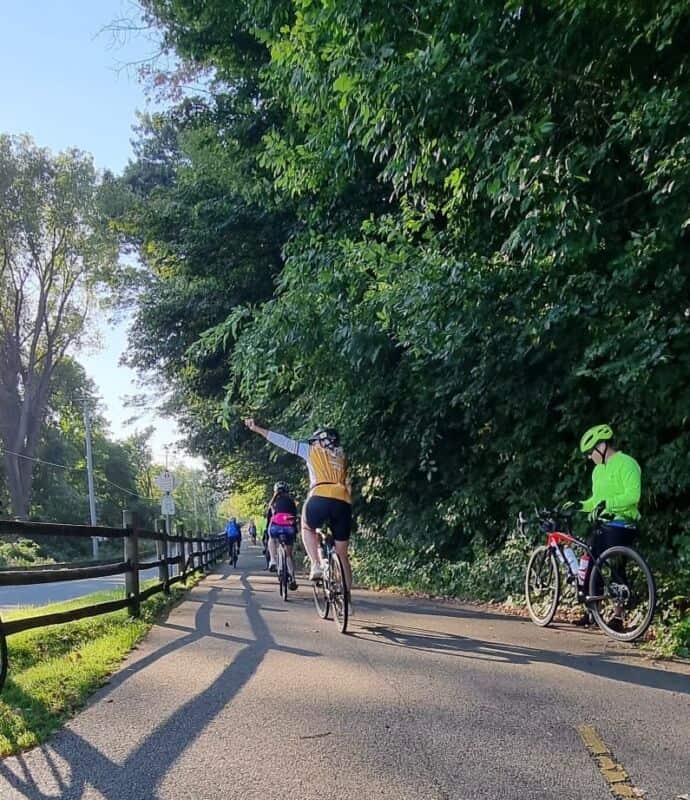 Vibrant cyclists enjoying a scenic ride on Newport's bike trail with lush greenery and safety gear, promoting active transportation and outdoor recreation in Rhode Island.