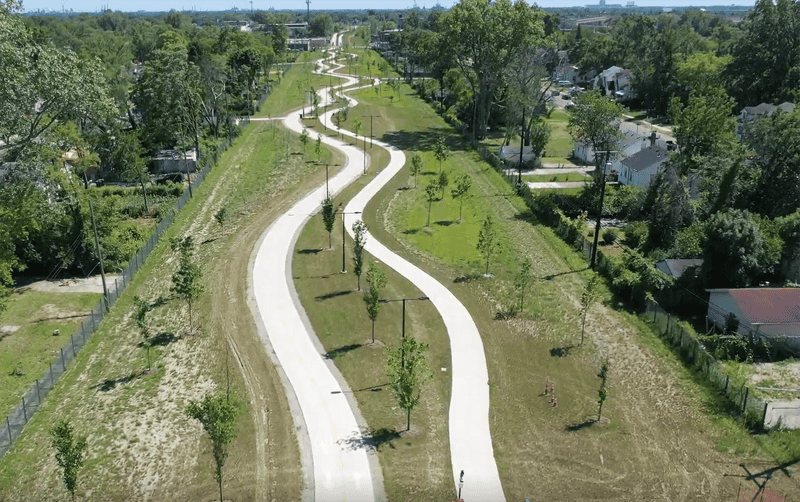A scenic, winding bike path through a green park in Newport with trees and open spaces, promoting outdoor recreation and community biking.