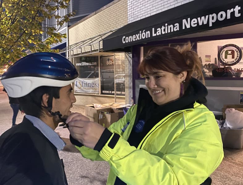 Bike Newport community event with woman helping cyclist, promoting bike safety and local cycling initiatives in Newport Rhode Island.