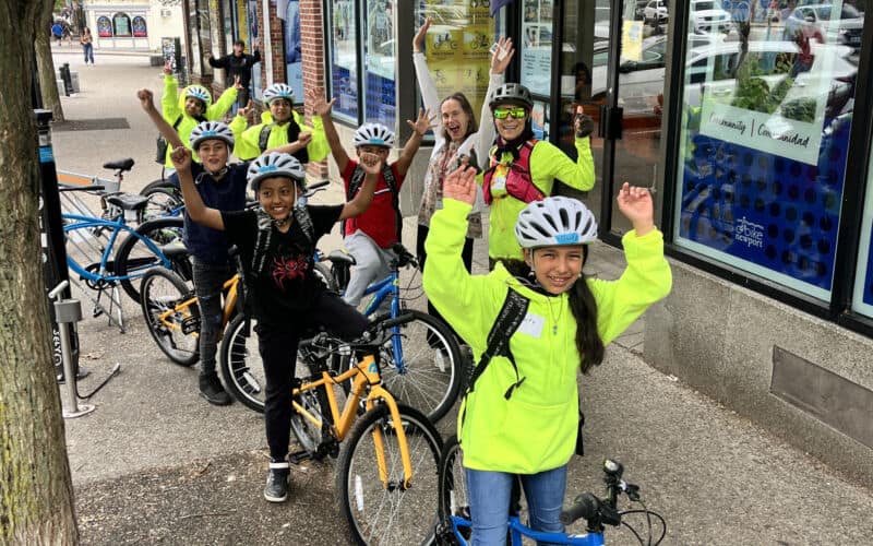 Young cyclists in safety gear cheer for the camera