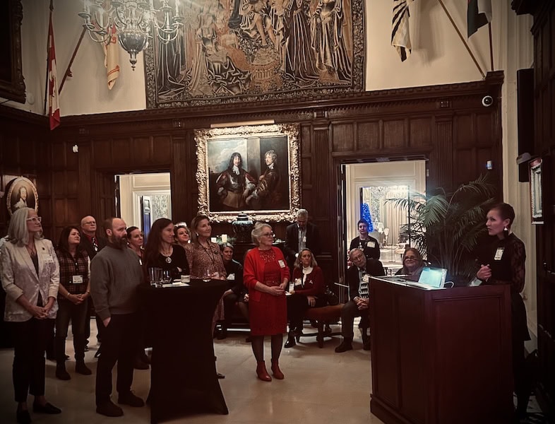 Historic interior of a grand hall with a group of people listening to a speaker during a formal event in Newport.