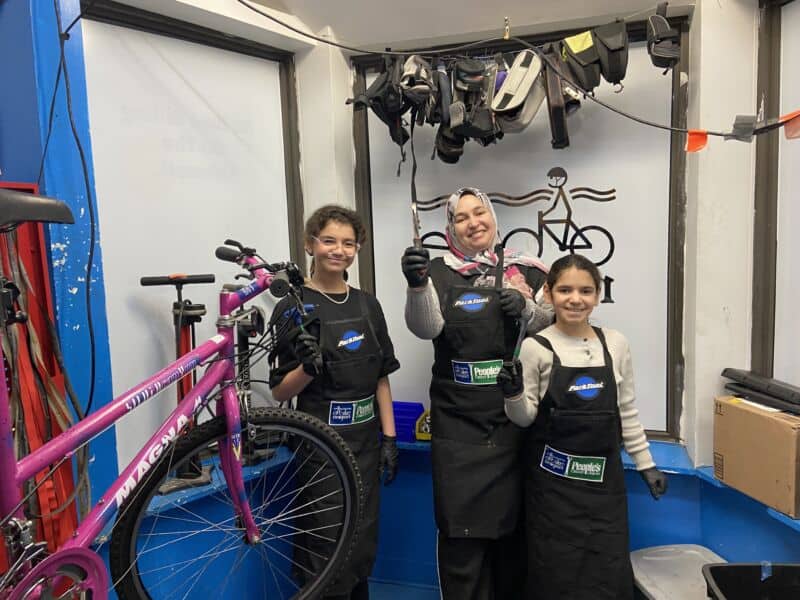 Bike repair shop with children and instructor, community cycling program, bike maintenance, cycling safety, Newport bike shop, youth bike workshop, Bicycle repair and education.