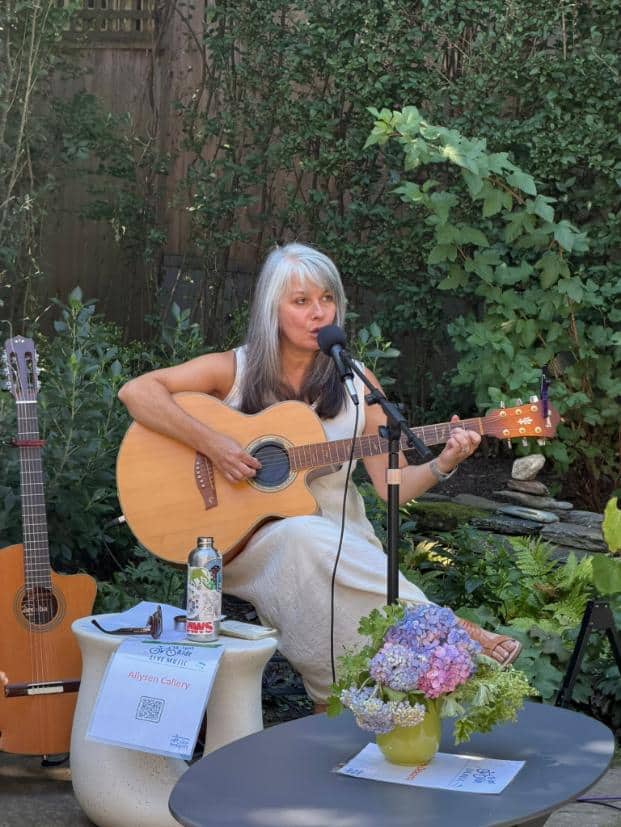 Singer-songwriter Allysen Callery plays acoustic guitar and sings in a leafy garden.