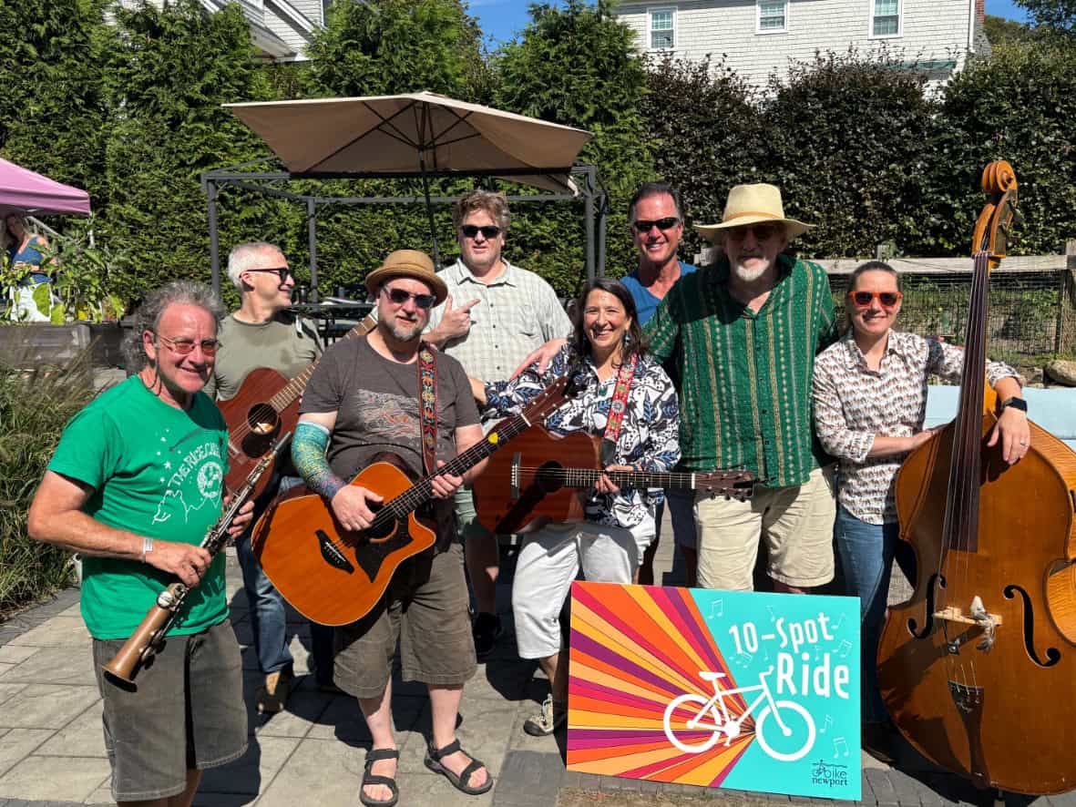 An eight-piece band poses with their instruments — clarinet, guitars and upright bass — beside a colorful "10-Spot Ride" sign.